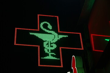 Glowing pixel cross of LED lamps on black background.