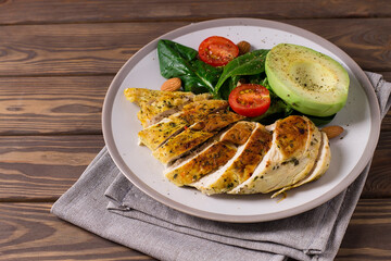 Healthy dietary salad with chicken fillet, avocado, nuts and fresh vegetables.Detox and healthy concept. Keto food. In a plate, on a wooden background.