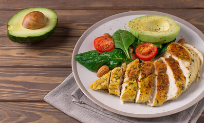Healthy dietary salad with chicken fillet, avocado, nuts and fresh vegetables.Detox and healthy concept. Keto food. In a plate, on a wooden background.