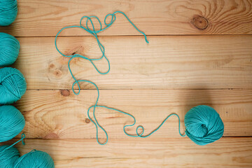 Flat lay of colored wool balls laying on the wooden background. Free space for text.