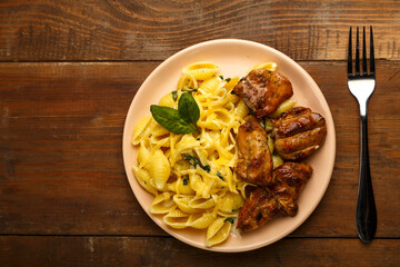 A plate of pasta in a creamy sauce with cheese and chicken on the table next to the fork. copy space.