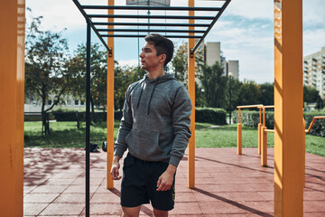 Young man bodybuilder having break during his workout in a modern calisthenics street workout park....