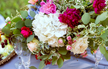 Flower arrangement, a bouquet of different flowers and two glasses, on a blurred background