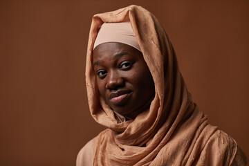 Fototapeta na wymiar Portrait of ethnic African-American woman wearing headscarf and looking at camera while posing in studio, copy space