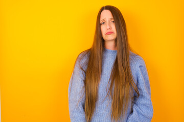 Displeased upset Young beautiful Caucasian woman wearing blue sweater frowns face as going to cry, being discontent and unhappy as can't achieve goals,  Disappointed model has troubles