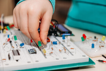 Close-up of hand of child engaged in creation of models from programmable radio parts from arduino