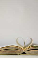 An old open book. I love reading. Close-up of book pages folded into a heart shape. Love of reading.