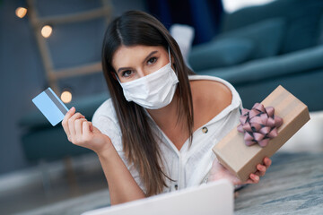 Pretty woman in mask shopping online with credit card