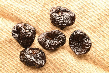 Sweet organic prunes on jute fabric, close-up.
