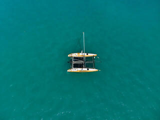 Aerial view of amazing deep blue lagoon at hot summer day with sailing catamaran across the sea....