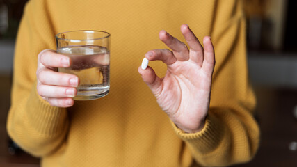 Young woman holding white pills in hands