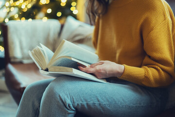 Woman reading paper book at cozy home