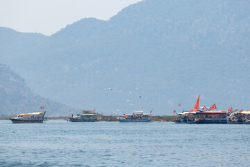 Tourist boats with Turkish flags on the background of mountains