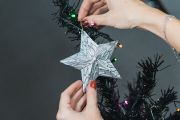 A young woman places a silver star on top of the Christmas tree