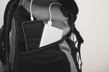 Smartphone charging with power bank in backpack, closeup