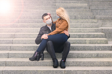 Young couple in masks on city street.