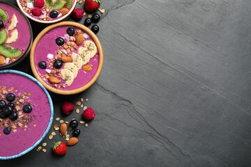 Acai smoothie bowls with granola and fruits on black table, flat lay. Space for text