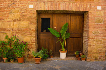 Fototapeta na wymiar The door of a residential building in the historic medieval village of Buonconvento, Siena Province, Tuscany, Italy. A cat can be seen looking out of the window in the door 