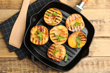 Delicious grilled peaches with mint on wooden table, flat lay
