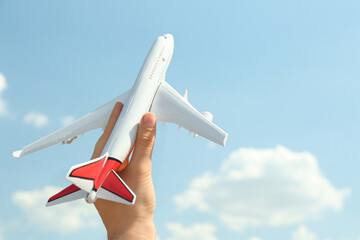 Woman holding toy airplane against blue sky, closeup