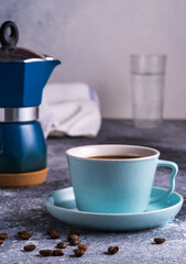 A cup of coffee and Geezer coffee maker under blurred bokeh background.