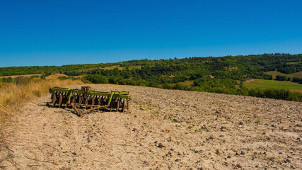 A harrow disc plough in the late summer landscape in Val d'Orcia near San Quirico d'Orcia, Siena...