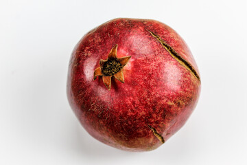 Red ripe pomegranate fruit against a white background. Anthers on ripe fruit up close. Rind outer skin of pomegranate. Macro of pomegranate fruit. Picture from top to bottom.