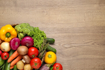 Different fresh vegetables on wooden table, flat lay. Space for text