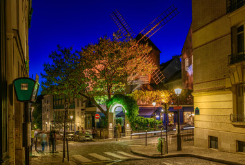 Night view of cozy street with old mill in quarter Montmartre in Paris, France
