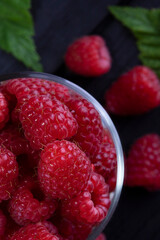 Raspberry. Fresh beautiful, red raspberries on a dark wood background. Green leaves. Place for text