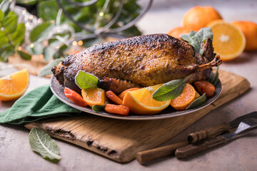 Winter Holiday table served for Christmas dinner with roasted duck, decorated with orange and herbs.  New year food