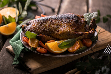 Winter Holiday table served for Christmas dinner with roasted duck, decorated with orange and herbs.  New year food