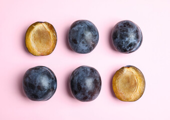 Delicious ripe plums on pink background, flat lay