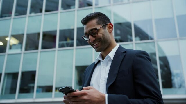 Mixed race businessman typing on cellular device smiling after long day at work