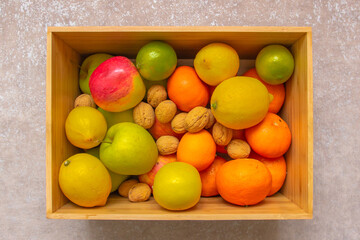 Fresh fruits in a wooden box. Mix of fruits. A lot of vitamins. Variety of fruits in wooden crate box. Fruits rich in vitamin C. Healthy vegetarian eating.Lemon, apples, nuts, orange for snack.