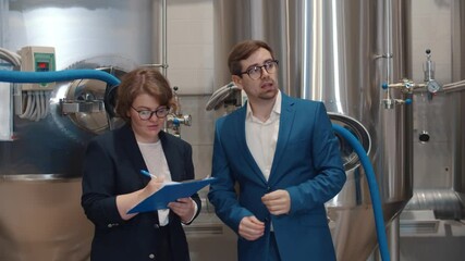Businesswoman with clipboard listening to manager of beer factory - Powered by Adobe