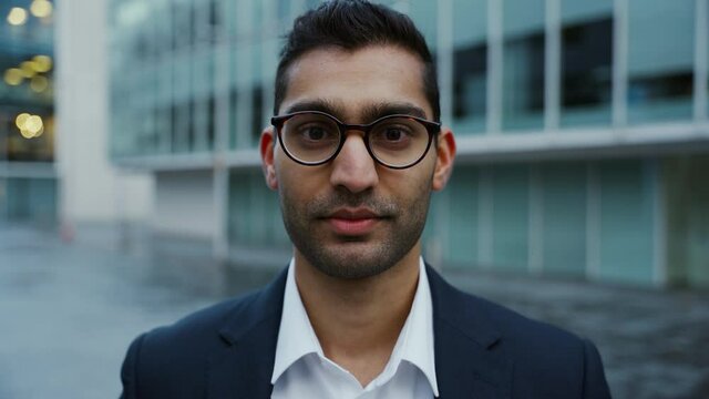 Mixed race businessman wearing spectacle standing in front of office block