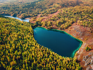 Aerial view of a huge lake with brilliant turquoise water which is located right in the middle of a dense saturated forest