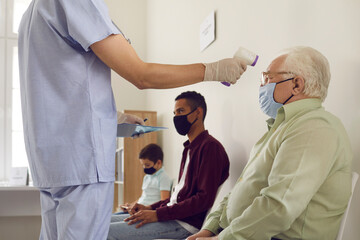 Obraz premium Doctor measuring senior man's temperature with non-contact electronic thermometer