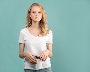 Waist-up portrait of beautiful young student girl with cup of coffee on color neutral tone Aqua...