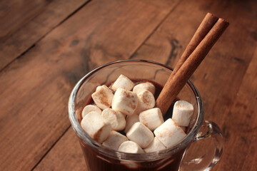 Dark hot chocolate with marshmallows in a glass cup on a wooden table. Hot winter drink on wood background. Selective focus
