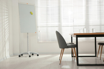Conference room interior with wooden table and flipchart