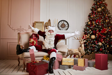 Santa Claus lay down to rest on the sofa with a bunch of gifts near the fireplace and christmas tree . New year and Merry Christmas , happy holidays concept