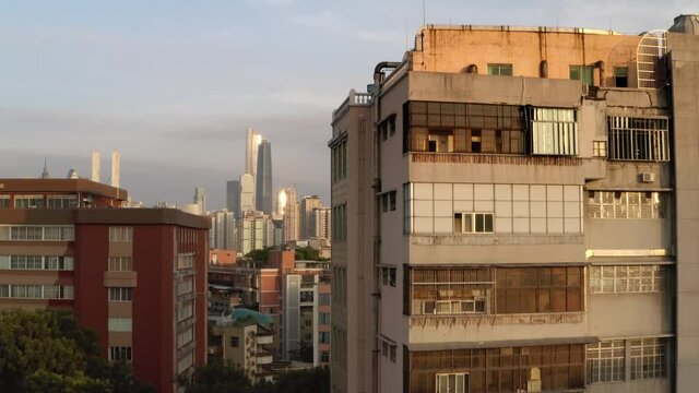 Reveal of Guangzhou city downtown CBD area from behind old buildings. Guangdong, China, Asia. Aerial shot.