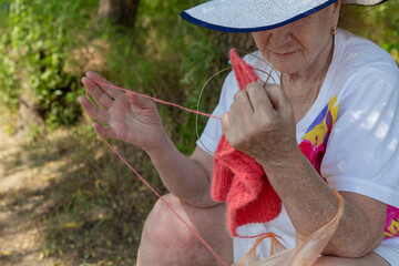 Grandmother knits a blouse in nature. Hobby. Rest at nature.