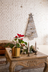 Festive table setting and beautiful Christmas decor in living room. Interior design.Holiday decorated living room with vibrant pointsettia and classic christmas design. Creative christmas tree