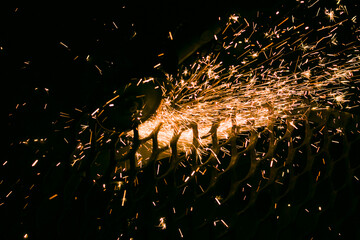 A worker cuts a steel mesh with a grinder. Sparks are clearly visible during operation. Preparing...