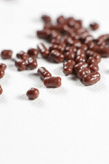 Chocolate dragee pile on white paper background
