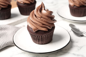 Delicious fresh chocolate cupcake on white marble table, closeup