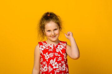 Energetic joyful adorable little girl laughing at joke on yellow background.
